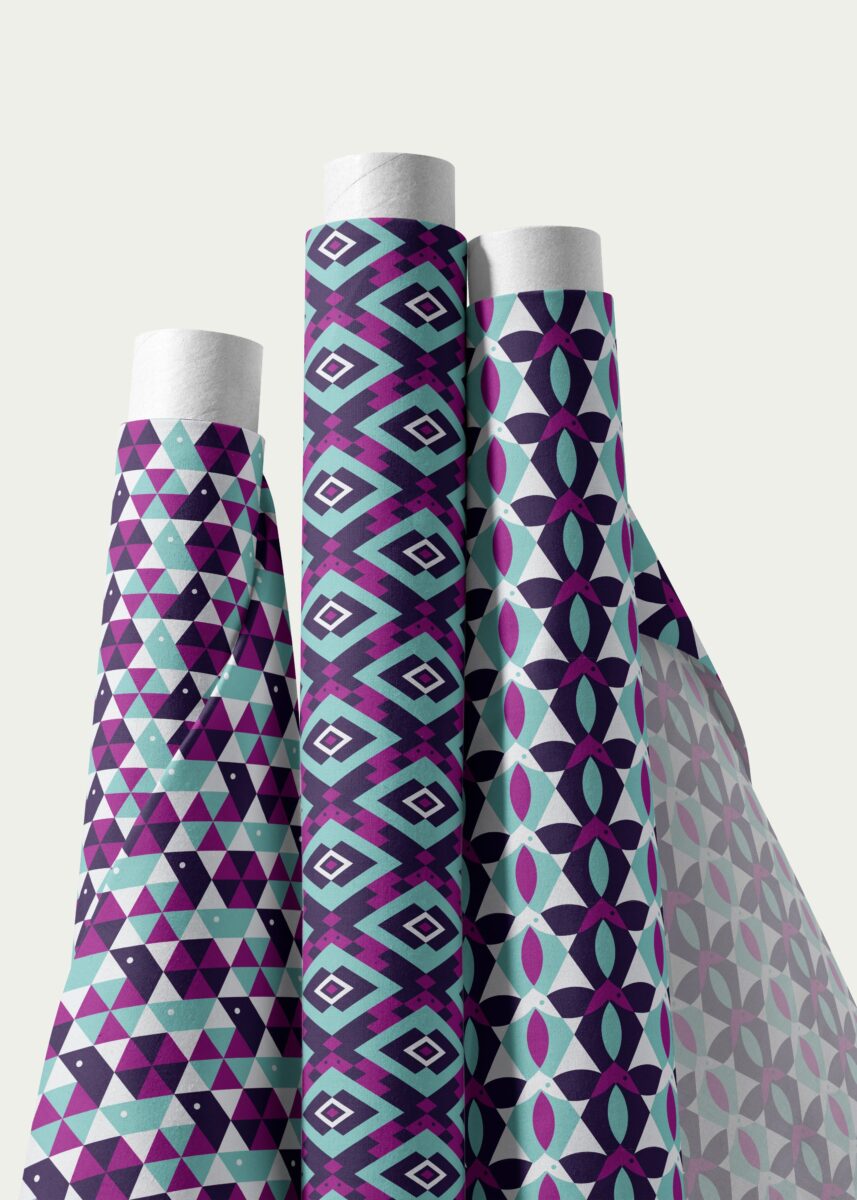 Stoffdesign von Vandyra Design. Geometrische Tiermotive. Jeweils mit Schnecke, Schildkröte, Fische. Bild zeigt drei Stoffrollen. Muster sind in den Farben Mint, Plump, Indigo und Weiß. Der Bildhintergrund ist helles Beige-Grau.